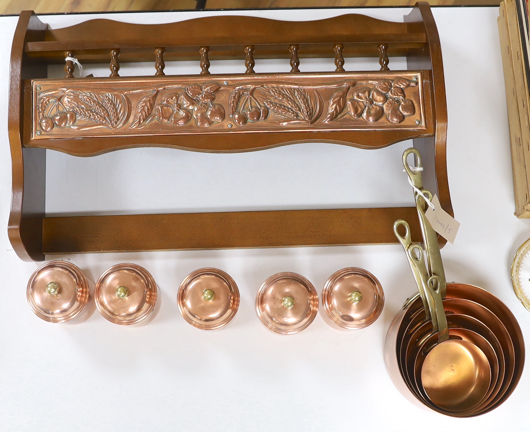 A graduated set of five French copper and brass saucepans and five lidded jars with copper mounted beech hanging rack